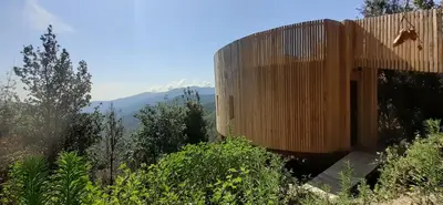 a wooden building on a hill with mountains in the background at LES CABANES DE LUTINA in Poggio-Marinaccio