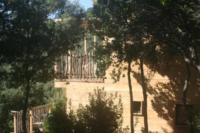 a building with a fence and trees in front of it at LES CABANES DE LUTINA in Poggio-Marinaccio