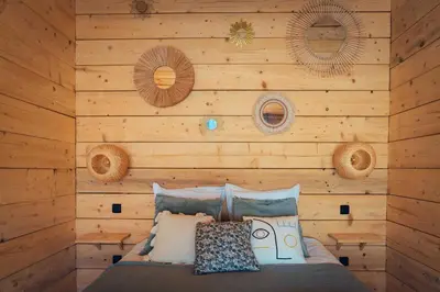 a bedroom with a wooden wall with a bed at LES CABANES DE LUTINA in Poggio-Marinaccio