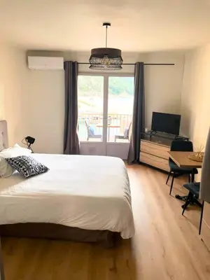 a bedroom with a bed and a balcony with a television at Appartements Les résidences du port La Siesta in Porto Ota