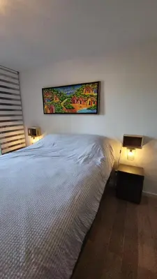 a bedroom with a white bed and a painting on the wall at Superbe T2 avec balcons, Vieux Port, Hyper centre Ajaccio in Ajaccio