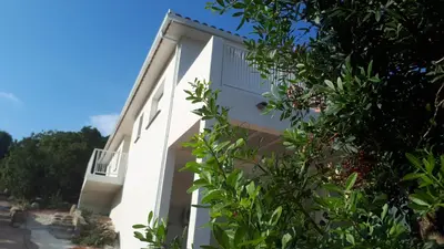 a white building with a balcony on the side at JOLIE VILLA dans un endroit paisible, à 3 mn de la Mer et de la Montagne in Ventiseri