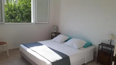 a white bedroom with a bed and a window at JOLIE VILLA dans un endroit paisible, à 3 mn de la Mer et de la Montagne in Ventiseri
