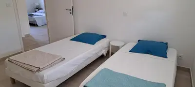 two beds with blue pillows in a room at JOLIE VILLA dans un endroit paisible, à 3 mn de la Mer et de la Montagne in Ventiseri
