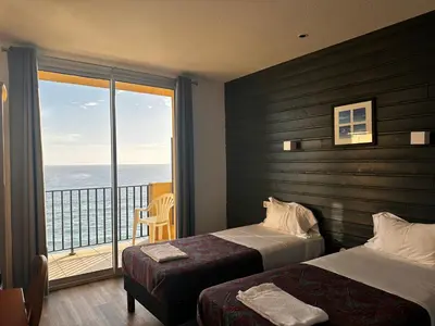 a hotel room with two beds and a balcony at Hôtel A RENA D'ORU in Coggia