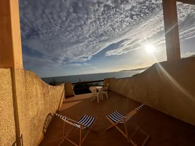 two chairs and a table on a balcony with the sunset at Hôtel A RENA D'ORU in Coggia
