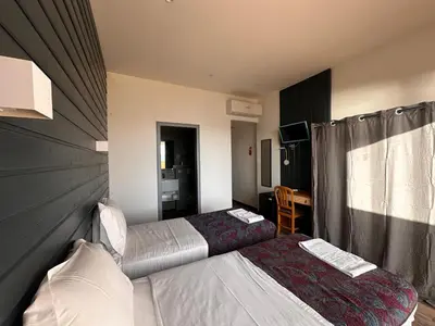 a hotel room with two beds and a table at Hôtel A RENA D'ORU in Coggia