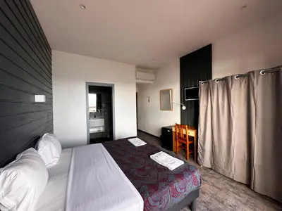 a hotel room with a bed and a desk at Hôtel A RENA D'ORU in Coggia