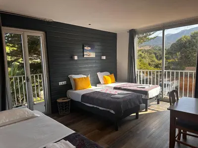 a hotel room with two beds and a balcony at Hôtel A RENA D'ORU in Coggia