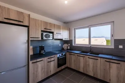 a kitchen with wooden cabinets and a window at Les Terres Rouges in Aléria
