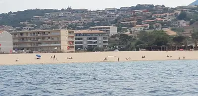 a view of a beach with people on the sand at face à la mer in Propriano