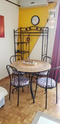 a table with two chairs and a clock on a wall at face à la mer in Propriano