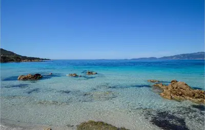 a beach with blue water and rocks in the ocean at Lovely Home In Coti Chiavari With Wifi in Coti-Chiavari