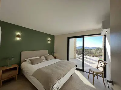 a bedroom with a large bed and a large window at Casa di Bà - villa 2 chambres avec piscine à 10 minutes des plages in Afa