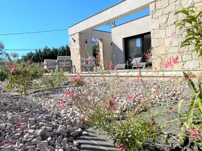 a stone house with pink flowers in the foreground at Casa di Bà - villa 2 chambres avec piscine à 10 minutes des plages in Afa