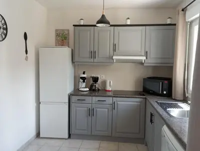 a kitchen with white cabinets and a white refrigerator at Villa climatisée A Nuciola Prunete Entre mer, montagne et piscine in Cervione