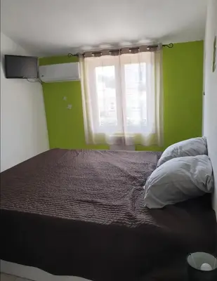 a bed in a room with green walls and a window at Villa climatisée A Nuciola Prunete Entre mer, montagne et piscine in Cervione