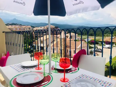 a table with plates and wine glasses on a balcony at Appartement centre ville avec piscine et vue mer in Sari Solenzara