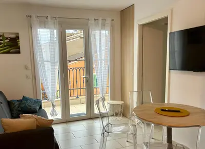 a living room with a tv and a table at Appartement centre ville avec piscine et vue mer in Sari Solenzara
