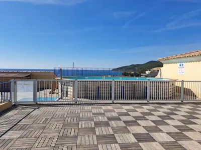 a deck with a swimming pool and a fence at Appartement centre ville avec piscine et vue mer in Sari Solenzara