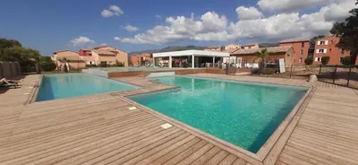 a large swimming pool with a wooden deck at Joli T2 climatisé au calme à 10 mm de Porto-Vecchio dans une résidence de tourisme in Lecci
