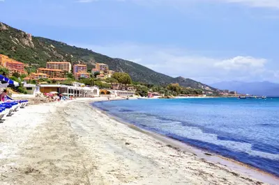 a beach with chairs and the ocean and buildings at Studio Rossi - Ajaccio - Welkeys in Ajaccio