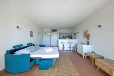 a bedroom with a bed and blue chairs in it at Studio Rossi - Ajaccio - Welkeys in Ajaccio