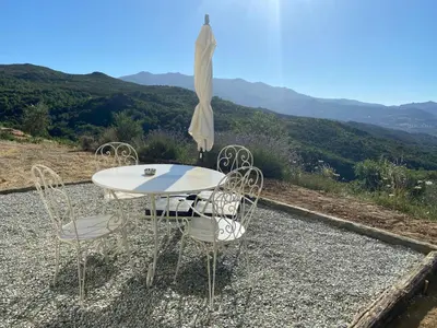 a table with chairs and an umbrella on a hill at Gîte à la ferme chez Félix et Marie-Ca in Vallecalle