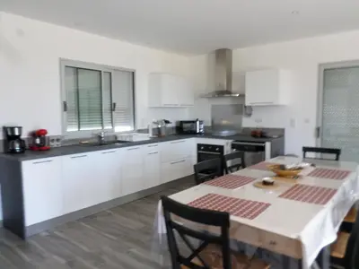 a kitchen with a table and a kitchen with white cabinets at Villa vue mer et nature route de Cigala in Sollacaro