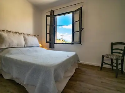 a bedroom with a bed and a window and a chair at Petit appartement à proximité de St Florent in Vallecalle