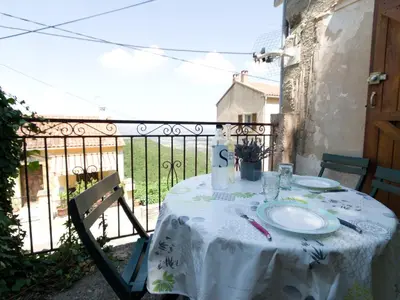 a table with a white table cloth on a balcony at Petit appartement à proximité de St Florent in Vallecalle