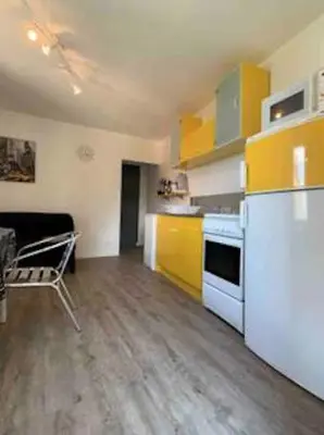 a kitchen with yellow cabinets and a white refrigerator at Petit appartement à proximité de St Florent in Vallecalle
