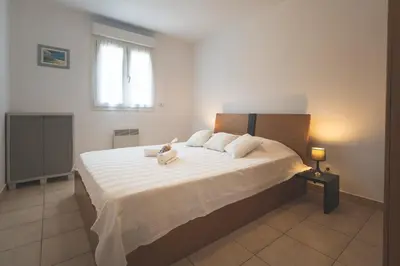 a bedroom with a large bed with white sheets at Maison à Cervione Prunete jardin piscine accès direct plage in Cervione