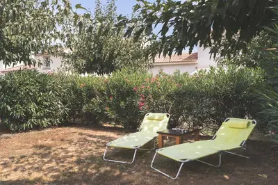 two green chairs and a table in a yard at Maison à Cervione Prunete jardin piscine accès direct plage in Cervione