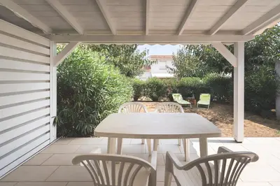 a wooden table and chairs on a patio at Maison à Cervione Prunete jardin piscine accès direct plage in Cervione