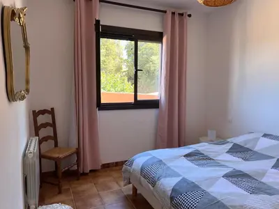 a bedroom with a bed and a window and a chair at Chez Caro in Sartène