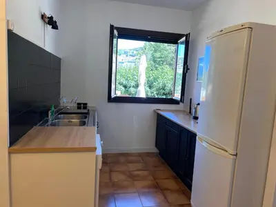 a kitchen with a white refrigerator and a window at Chez Caro in Sartène