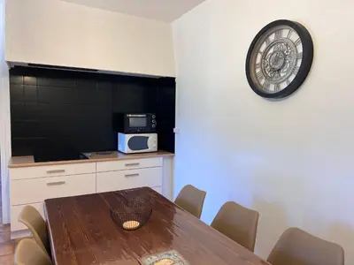 a dining room with a table and a clock on the wall at Chez Caro in Sartène