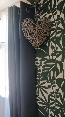 a wicker heart hanging on a wall next to a curtain at Le petit chalet d' Anto-Francè in Levie