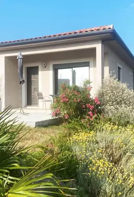 a house with a patio and some bushes and flowers at Villa Jade in Sartène