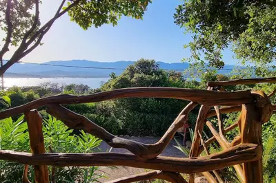 a wooden bench with a view of the ocean at Villa charmante à Porto-Vecchio avec piscine in Porto-Vecchio