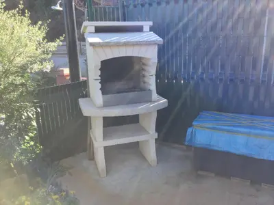 a wood stove sitting on a patio next to a fence at Maison au calme avec terrain et vue sur la mer in Poggio-Mezzana