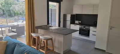 a kitchen with a counter with stools and a tv at Appartement T3 proche du Port in Porto-Vecchio