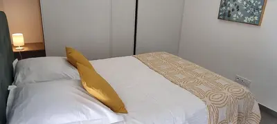 a white bed with a yellow pillow on it at Appartement T3 proche du Port in Porto-Vecchio