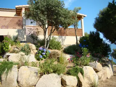 a garden with rocks and flowers in front of a house at VILLA 4pers, STUNNING SEA VIEW, BEACH ON FOOT 4* in Olmeto