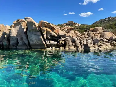 a body of water with rocks and blue water at Charmante petite maison magnifique vue mer in Propriano