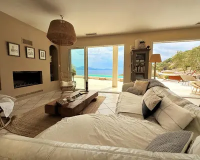 a living room with a large couch and a fireplace at Villa Casa Bianca Sagone Piscine privée et Vue mer Familiale in Sagone