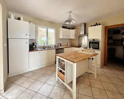 a kitchen with white cabinets and a wooden table at Villa Casa Bianca Sagone Piscine privée et Vue mer Familiale in Sagone