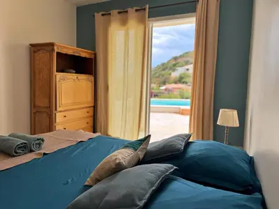 a bedroom with a bed with blue sheets and a window at Villa Casa Bianca Sagone Piscine privée et Vue mer Familiale in Sagone