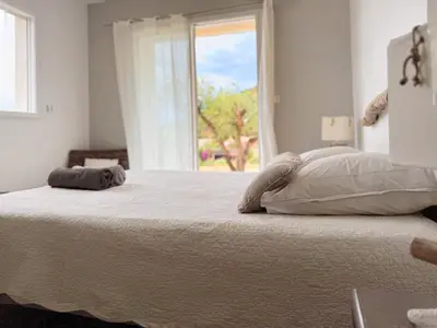 a white bedroom with a large bed with a window at Villa Casa Bianca Sagone Piscine privée et Vue mer Familiale in Sagone